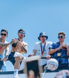 three men sitting on top of a roof with medals around their necks and one man holding a camera