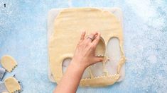 a woman is kneading dough in the shape of a skull on a blue surface