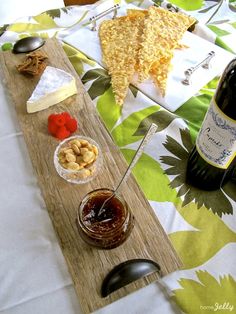 an assortment of cheeses, crackers and wine on a table with a flowered cloth