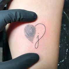 a person with a fingerprint on their arm holding up a black inked tattoo