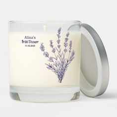 a white candle with purple flowers on the front and label that says, allana's bridal shower