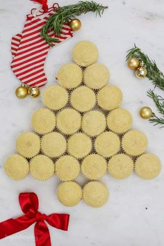 a christmas tree made out of cupcakes on a marble table with ornaments around it