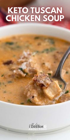 a close up of a bowl of soup with a spoon in it and the words keto tuscan chicken soup