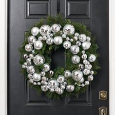 a christmas wreath on the front door with silver ornaments hanging from it's sides