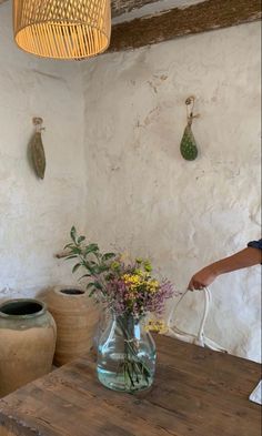 a man is pouring water into a vase on a table in front of two clay urns