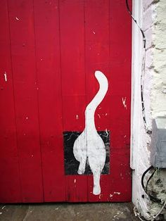 an image of a cat painted on the side of a red door with white paint