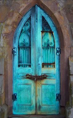 an old blue door with iron bars on the top and bottom, in front of a stone wall