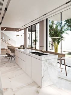 a large kitchen with marble counter tops and white cabinets, along with stairs leading up to the second floor