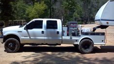 a white truck with a camper attached to it's bed parked in the dirt