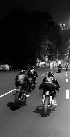 black and white photograph of motorcyclists going down the road at night time