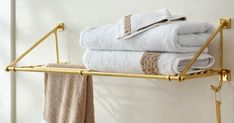 towels are stacked up on a towel rack in a bathroom with gold fixtures and white walls