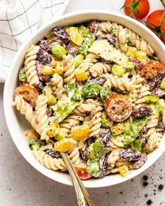 a bowl filled with pasta salad next to tomatoes