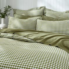 a green and white checkered comforter set on a bed with two vases