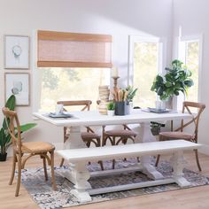 a dining room table and bench with plants on the windowsills in front of it