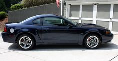 a blue sports car parked in front of a garage with an american flag on it