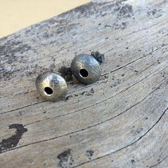 two metal bells sitting on top of a wooden table next to each other with holes in them