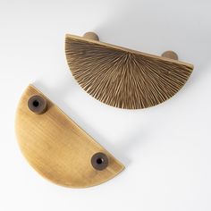 two pieces of wood with holes in the middle on a white surface, one is shaped like a fan