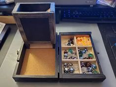 an open wooden box with dices in it on a desk next to a keyboard