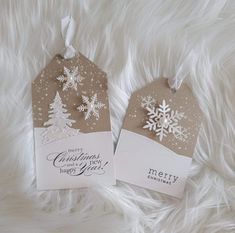 two tags with snowflakes on them are sitting on a fur surface, one is white and the other is brown