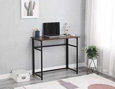 a laptop computer sitting on top of a wooden desk next to a potted plant