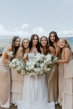 a group of women standing next to each other in dresses and holding bouquets on top of a roof