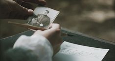 a person is holding an old photo and writing