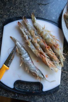 there are three different types of shrimp on the cutting board next to a knife and another type of fish