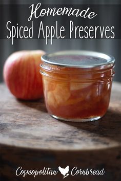 homemade spiced apple preserves in a glass jar on a wooden table with an apple next to it