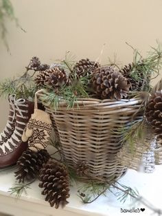 a basket filled with pine cones sitting on top of a white mantle next to a pair of shoes