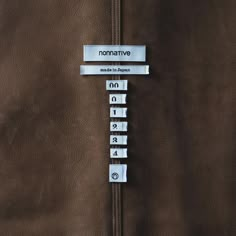 there is a brown leather jacket with metal numbers on the front and back buttons that say nonnative