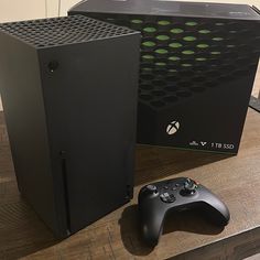 a black computer case next to a game controller on a wooden table in front of it