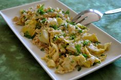 a white plate topped with pasta covered in sauce and parsley next to a fork