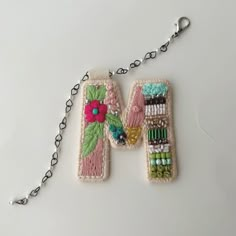 a pair of beaded purses hanging from a chain on a white table top