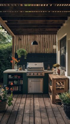 an outdoor kitchen with grill, sink and potted plants on the outside deck area