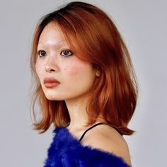 a woman with red hair is wearing a blue fur coat and posing for the camera