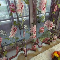 the curtains are decorated with flowers and fruit on the floor in front of a window