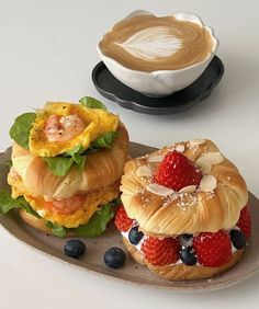 two pastries are sitting on a plate next to a cup of coffee