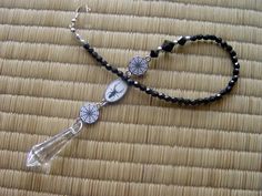 a beaded necklace with dandelions and glass beads on a bamboo mat background