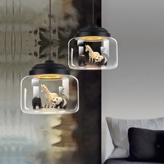 two glass pendant lights with animals in them