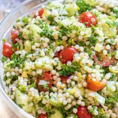 a salad with tomatoes, cucumbers, and broccoli in a glass bowl