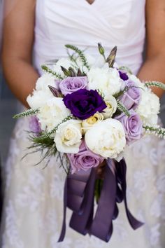 a bride holding a purple and white bouquet