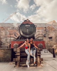 two women pose for a photo in front of a train