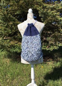 a mannequin wearing a blue and white crochet halter top in the grass