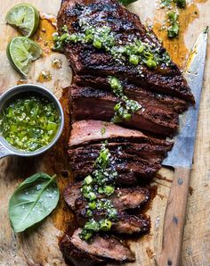 grilled steak with salsa and limes on a cutting board