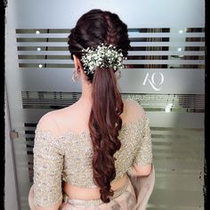 the back of a woman's head with long hair and flowers in her hair