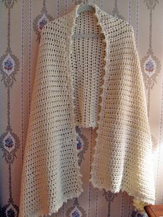 a white crocheted jacket hanging on a wall