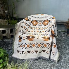 a blanket sitting on top of a gravel ground next to potted plants and trees