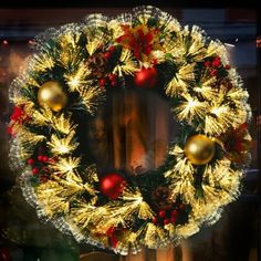 a christmas wreath on display in a store window with lights and ornaments around the wreath