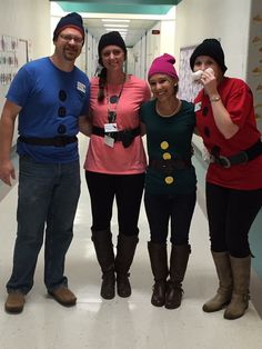 four people in costumes posing for a photo at an office hallway with posters on the wall behind them