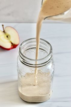 an apple is being poured into a mason jar